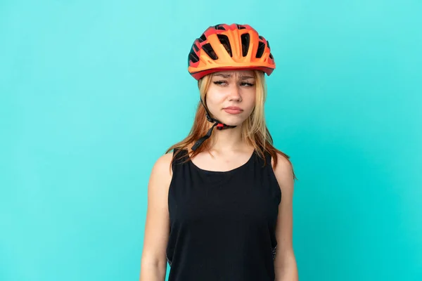 年轻的骑自行车的女孩在孤独的蓝色背景上一边看一边怀疑 — 图库照片