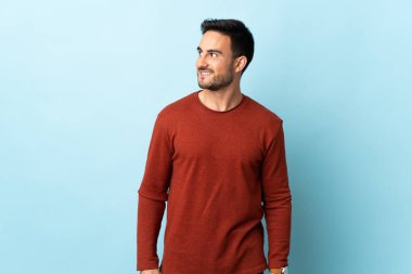 Soyutlanmış arka planda genç yakışıklı bir adam yana bakıyor ve gülümsüyor.