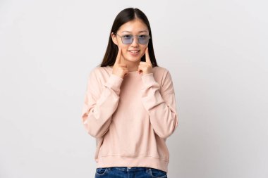 Soyutlanmış beyaz arka planda mutlu ve hoş bir ifadeyle gülümseyen genç Çinli kız.