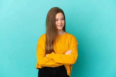 İzole edilmiş mavi arka planda genç bir kız yan tarafa bakıyor.