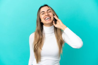 Mavi arka planda izole edilmiş cep telefonu kullanan beyaz bir kadın.