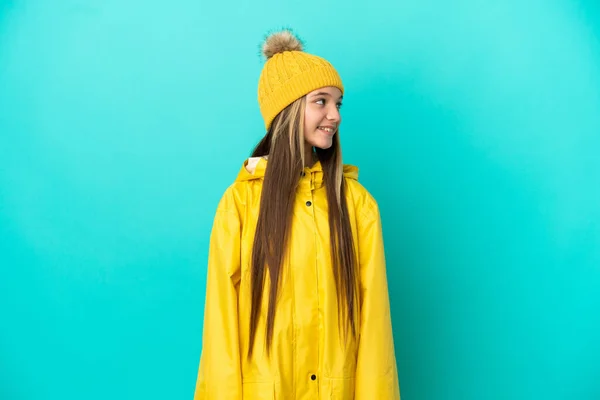 Niña Usando Abrigo Impermeable Sobre Fondo Azul Aislado Mirando Lado —  Fotos de Stock