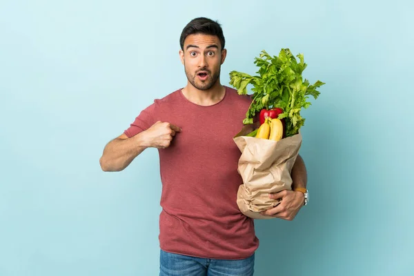 Giovane Uomo Caucasico Che Acquista Alcune Verdure Isolate Sfondo Blu — Foto Stock