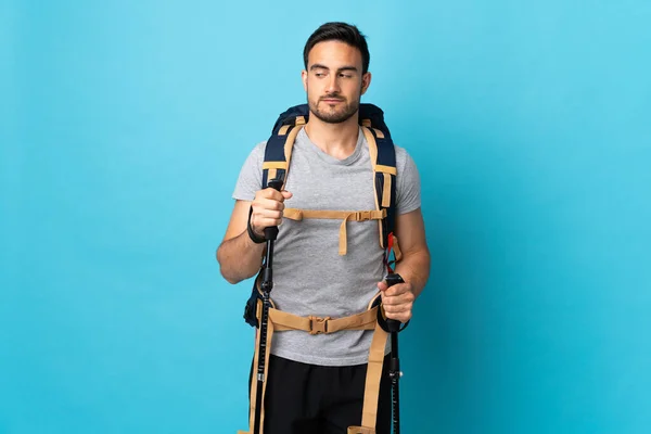 Jovem Caucasiano Com Mochila Postes Trekking Isolado Fundo Azul Fazendo — Fotografia de Stock