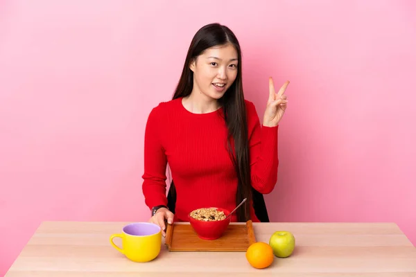 Молодая Китаянка Завтракает Столом Улыбаясь Показывая Знак Победы — стоковое фото