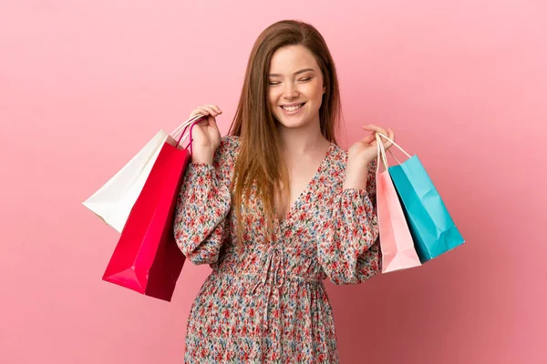 ティーン少女上の隔離されたピンクの背景を保持ショッピングバッグと笑顔 — ストック写真