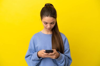 Küçük kız cep telefonu kullanarak izole edilmiş sarı arka plan