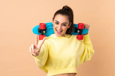 Pembe arka planda, zafer jesti yapan genç, beyaz bir kadın.