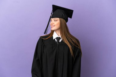 Tecrit edilmiş mor arka planda genç üniversite mezunu.