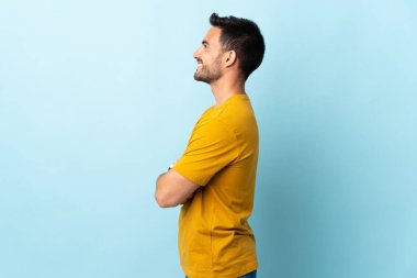 Genç ve yakışıklı bir adam, soyutlanmış arka planda yan pozisyonda.