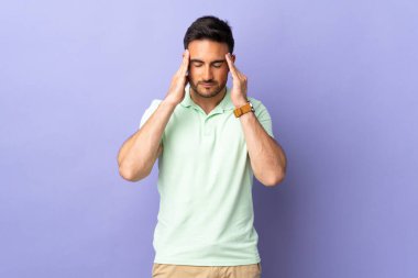 Mor arka planda başı ağrıyan genç ve yakışıklı bir adam.