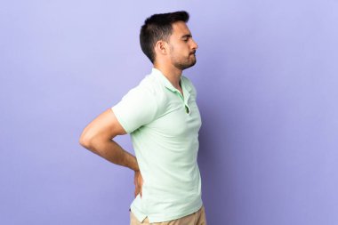 Mor arka planda izole edilmiş genç bir adam gayret gösterdiği için sırt ağrısı çekiyor.