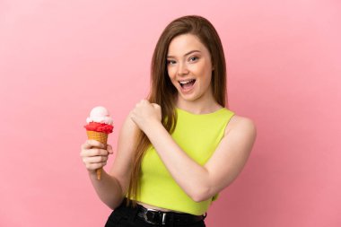 Kornet dondurmalı ergen kız izole edilmiş pembe arka planda zaferi kutluyor.