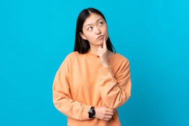 Soyutlanmış mavi arka planda genç bir Çinli kız araştırırken şüphe duyuyor.