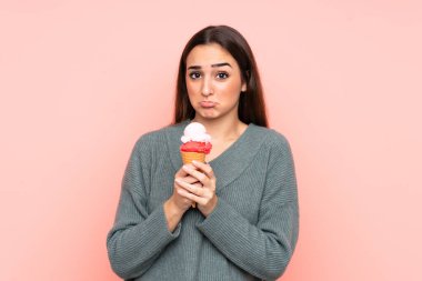 Kornet dondurması tutan genç bir kadın pembe arka planda izole edilmiş.