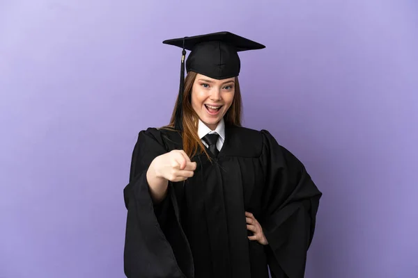 Junge Universitätsabsolventin Über Isolierten Lila Hintergrund Überrascht Und Zeigt Nach — Stockfoto