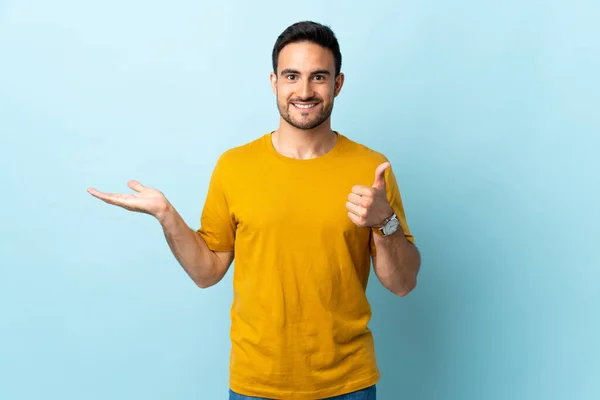 Joven Hombre Guapo Sobre Fondo Aislado Sosteniendo Espacio Copia Imaginario — Foto de Stock