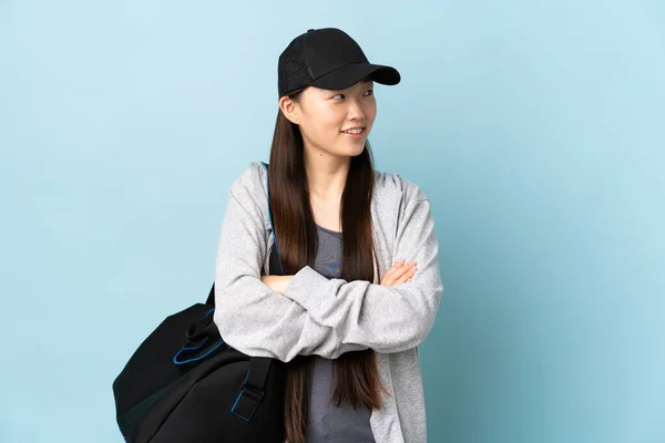年轻的中国女子 背着运动包 蓝色背景 微笑着抬头看 — 图库照片