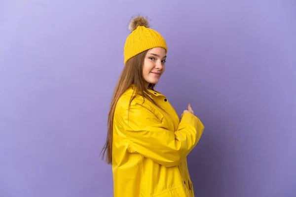 Chica Adolescente Con Abrigo Impermeable Sobre Fondo Púrpura Aislado Apuntando —  Fotos de Stock