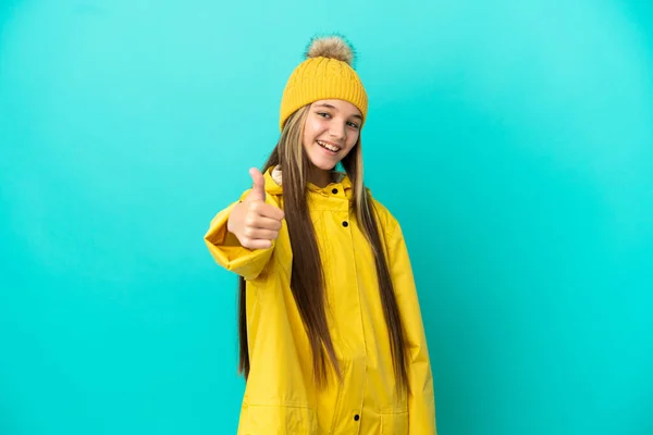 Niña Usando Abrigo Impermeable Sobre Fondo Azul Aislado Con Pulgares —  Fotos de Stock