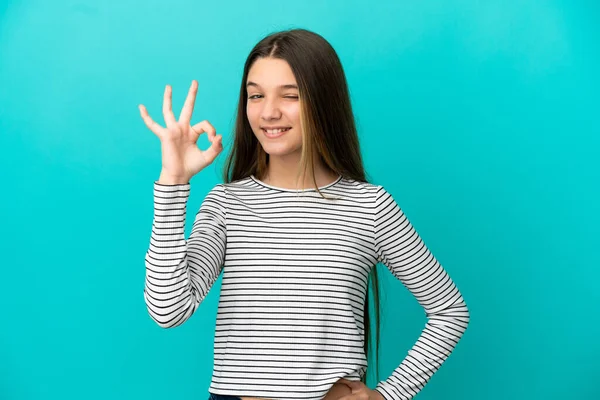 Mała Dziewczynka Nad Odizolowanym Niebieskim Tle Pokazuje Znak Palcami — Zdjęcie stockowe