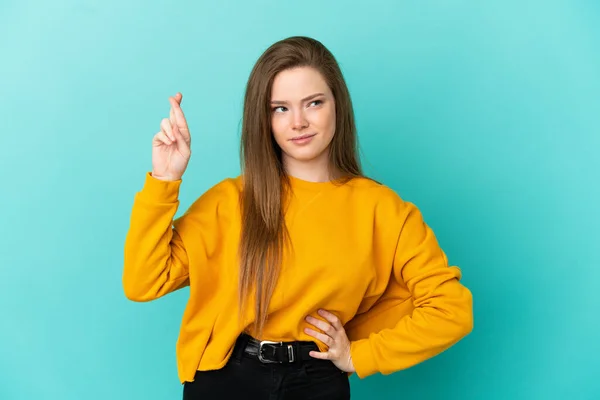 Tonårstjej Över Isolerad Blå Bakgrund Med Fingrar Korsning Och Önskar — Stockfoto