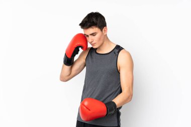 İzole edilmiş beyaz duvarda boks eldivenli genç bir sporcu.