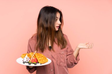 Pembe arka planda yüzü sürpriz bir ifadeyle gözleme tutan beyaz bir kadın.