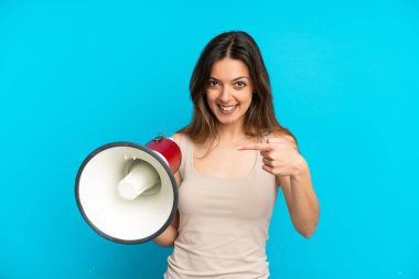 Mavi arka planda izole edilmiş beyaz bir kadın elinde bir megafonla ve şaşırmış bir yüz ifadesiyle