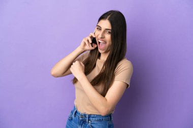Mor arka planda izole edilmiş bir şekilde cep telefonu kullanan beyaz bir kadın zaferi kutluyor.