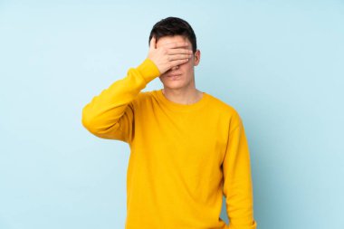 Genç, beyaz, yakışıklı bir adam mor arka planda izole edilmiş, gözleri elle kapatıyor. Bir şey görmek istemiyorum.