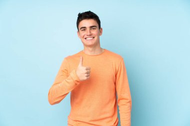 Mor arka planda izole edilmiş genç, beyaz, yakışıklı bir adam baş parmak hareketi yapıyor.