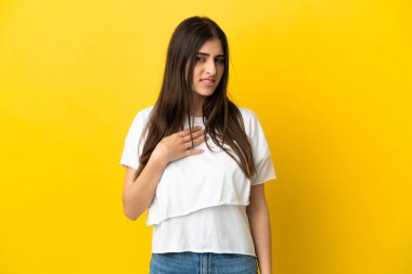 Sarı arka planda izole edilmiş genç beyaz kadın kendini işaret ediyor.
