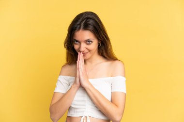 Sarı arka planda izole edilmiş genç beyaz kadın avuç içlerini bir arada tutuyor. İnsan bir şey ister.