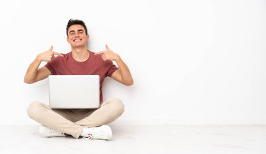 Flor 'da dizüstü bilgisayarıyla oturan genç adam gururlu ve kendini beğenmiş.