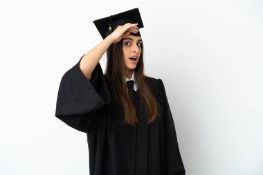 Beyaz arka planda izole edilmiş genç üniversite mezunu. Yan tarafa bakarken sürpriz jest yapıyor.