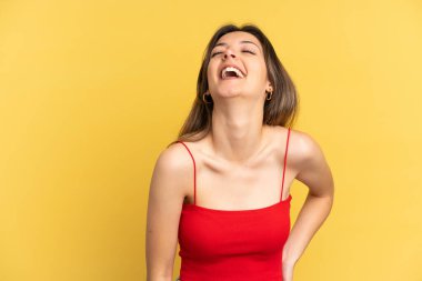 Sarı arka planda izole edilmiş genç beyaz kadın gülüyor.