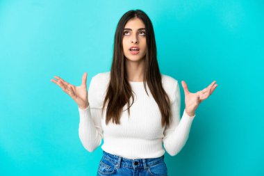 Mavi arka planda izole edilmiş genç beyaz kadın bunalımda.