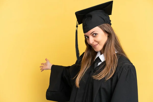 Joven Graduado Universitario Aislado Sobre Fondo Amarillo Extendiendo Las Manos — Foto de Stock