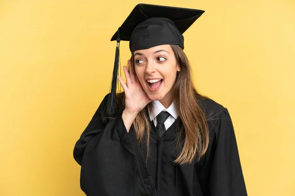 Jeune Diplômé Isolé Sur Fond Jaune Écoutant Quelque Chose Mettant — Photo