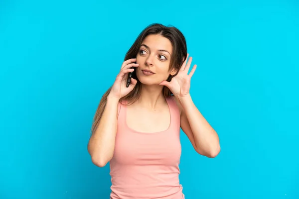 Jovem Caucasiana Usando Telefone Celular Isolado Fundo Azul Ouvir Algo — Fotografia de Stock