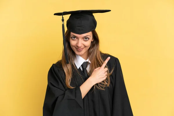 Graduado Universitario Joven Aislado Sobre Fondo Amarillo Apuntando Hacia Lado —  Fotos de Stock