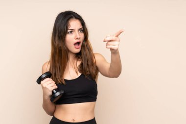 Bej arka planda izole haldeyken halter kaldıran genç bayan