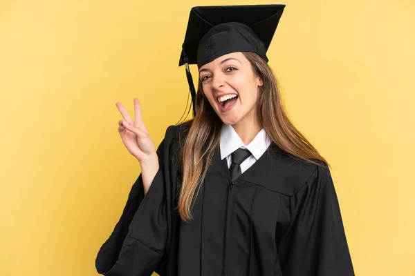Junger Universitätsabsolvent Auf Gelbem Hintergrund Lächelt Und Zeigt Siegeszeichen — Stockfoto