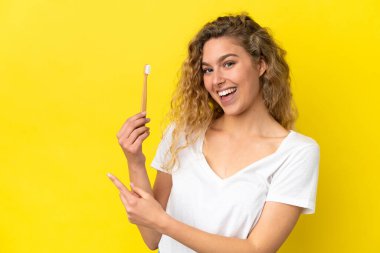 Sarı arka planda izole edilmiş diş fırçalayan beyaz bir kadın var.