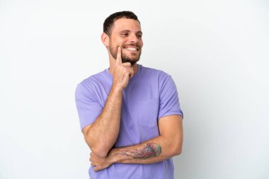 Genç Brezilyalı bir adam beyaz arka planda izole edilmiş bir şekilde bakarken bir fikir düşünüyor.