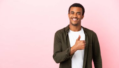 Telif uzayındaki Afro-Amerikalı adam pembe arka planda baş parmak hareketi yapıyor.