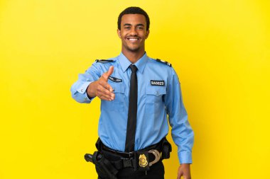 Afrika kökenli Amerikalı polis, sarı arka planda iyi bir anlaşma için el sıkışıyor.