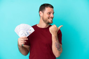 Genç Brezilyalı bir adam, izole edilmiş geçmişinden çok fazla para alıyor ve bir ürünü sunmak için kenarı işaret ediyor.