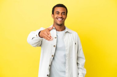 Sarı arka planda Afro-Amerikalı yakışıklı adam iyi bir anlaşma için el sıkışıyor.